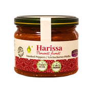 Glasburk med harissa av rökt paprika, orientaliskt kryddig chilisås, närbild på vit bakgrund.